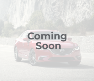 red_mazda_car_parked_in_a_lay_by_next_to_a_mountain_coming_soon_message