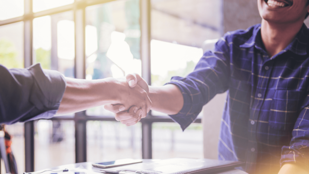 two_people_shaking_hands_across_a_desk